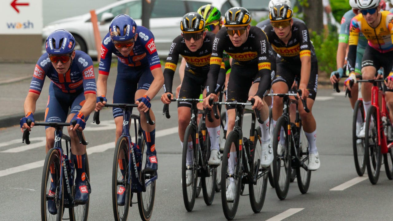 Cyclists competing in an urban road race stage showing the intense competition where domestiques sacrifice their own positions to support team leaders