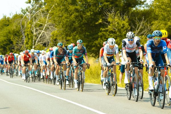 Professional cyclists riding together in a tight peloton formation, illustrating how domestiques shield team leaders from wind resistance