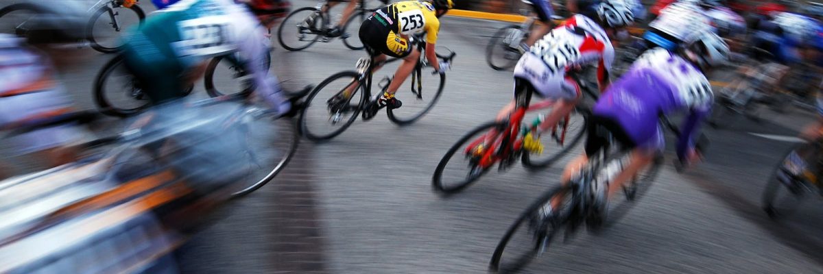 Professional cyclists in a Grand Tour stage race climbing mountain roads with team vehicles in convoy