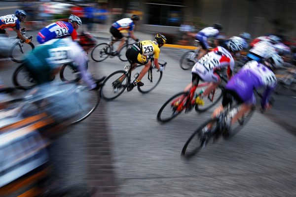 Professional cyclists in a Grand Tour stage race climbing mountain roads with team vehicles in convoy
