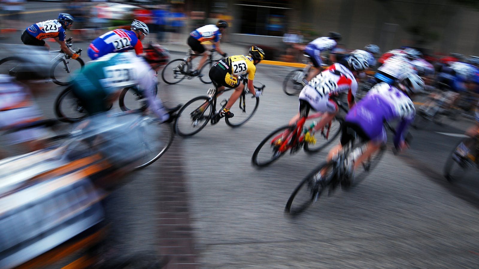 Professional cyclists racing in a mountain stage of a Grand Tour stage race, with steep alpine roads and team support vehicles following